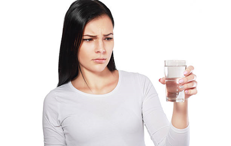 Women looking at glass of water - water smells like sulfur
