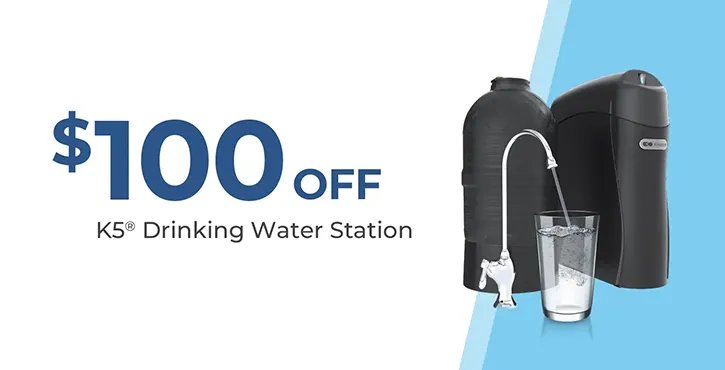 $100 off K5 Drinking Water Station. Image shows a water filter system, a black tank, a glass of water, and a faucet on a blue and white background.
