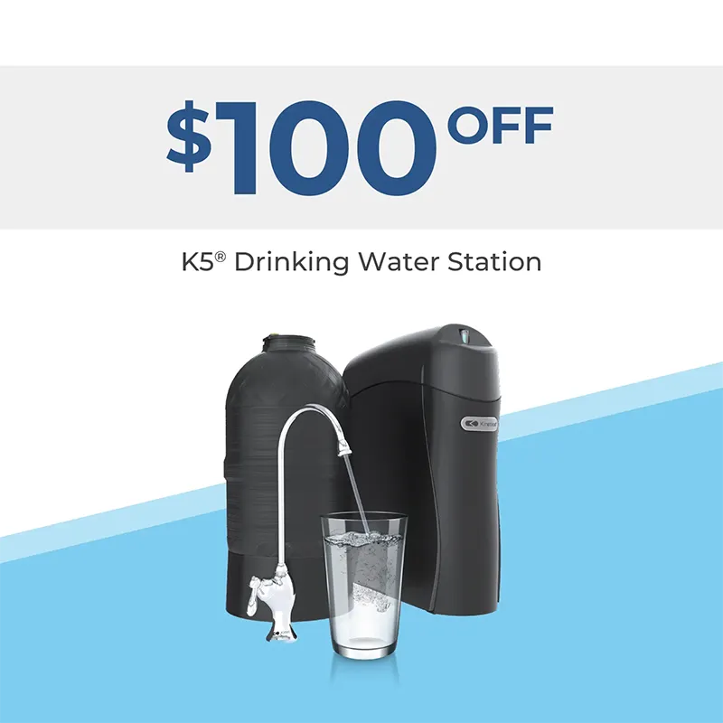 $100 off K5 Drinking Water Station. Image shows a water filtration system with a faucet pouring water into a glass, with the systems components in the background.