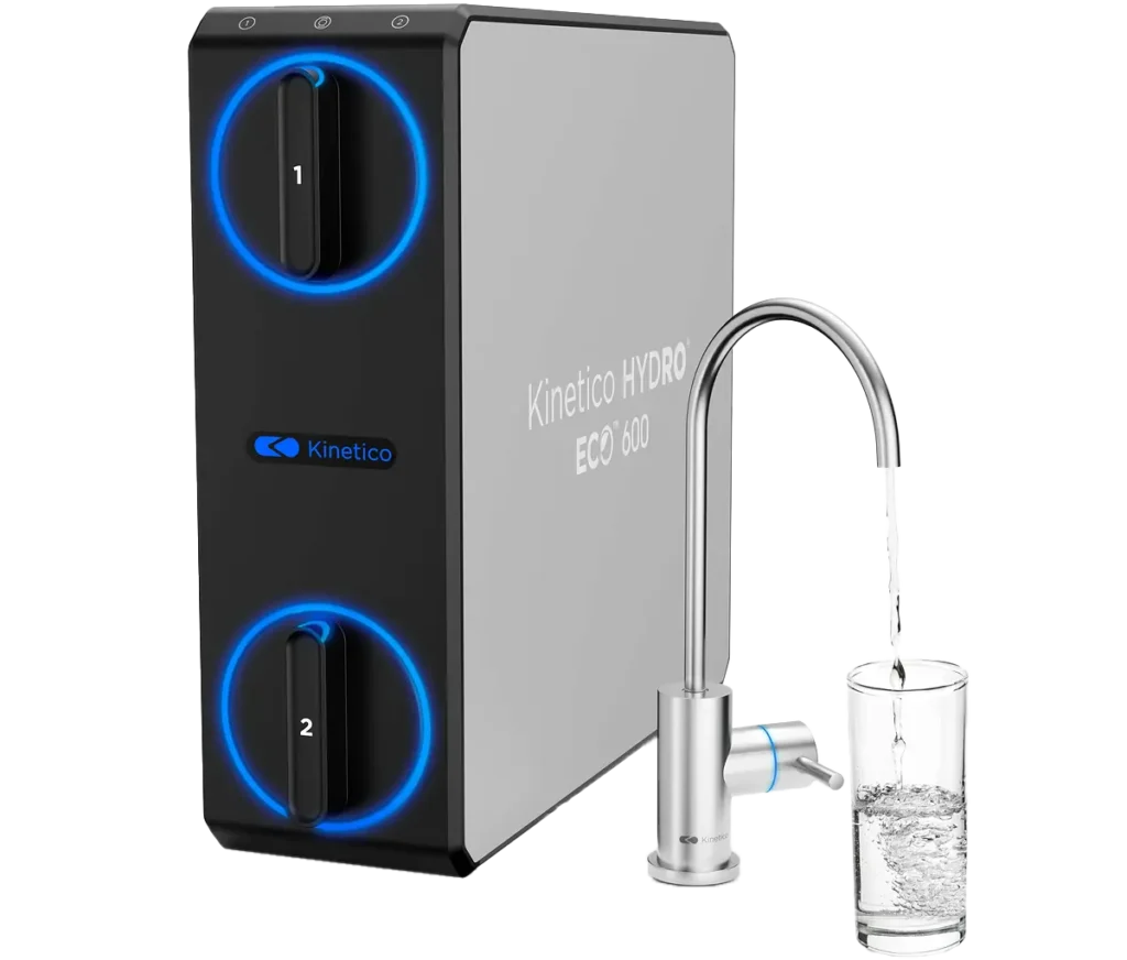 A Kinetico HYDRO ECO 600 water filtration unit with two circular blue-lit controls and a faucet dispensing water into a clear glass.